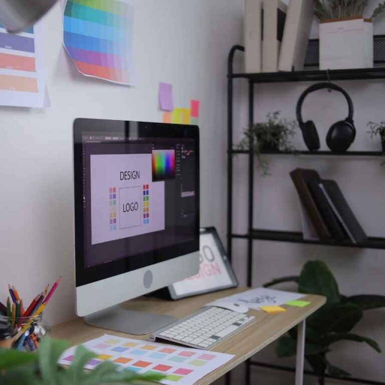 Kreativer Arbeitsplatz mit Bildschirm, Farbmustern und Designmaterial